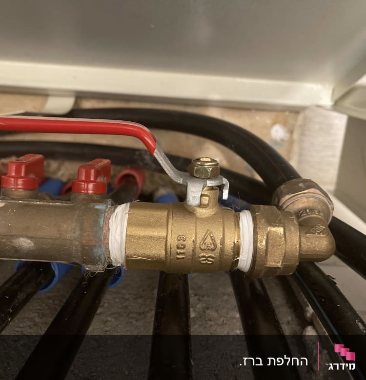 ברז פליז עם ידית אדומה וצינורות שחורים